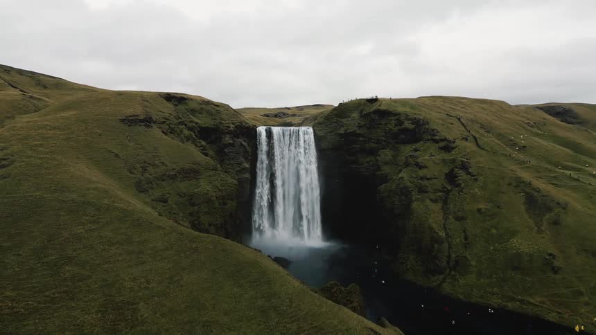 Aerial view of a green mountain with an impressive waterfall
