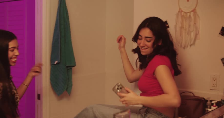 Teenage girls having fun dancing while putting on makeup in the bathroom at home