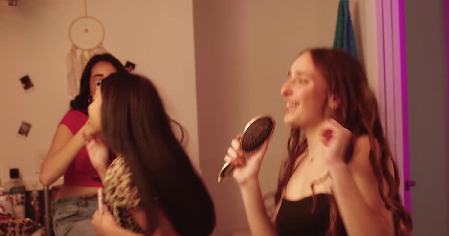 Three happy women dancing and putting on makeup in the bathroom