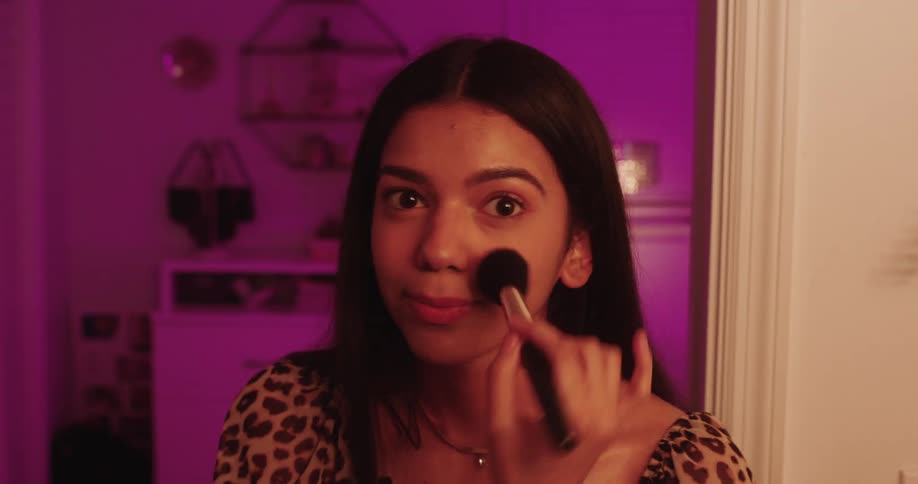 Portrait of a young and happy woman putting on makeup