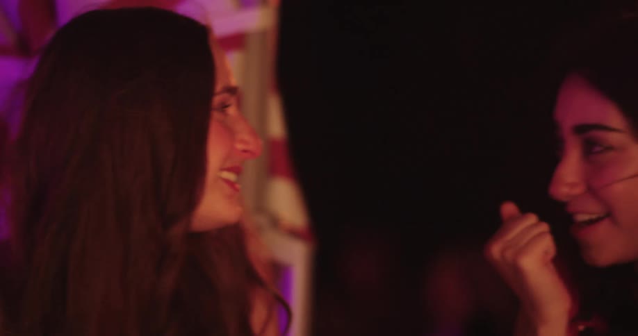 Two female friends talking at an outdoor bar at night
