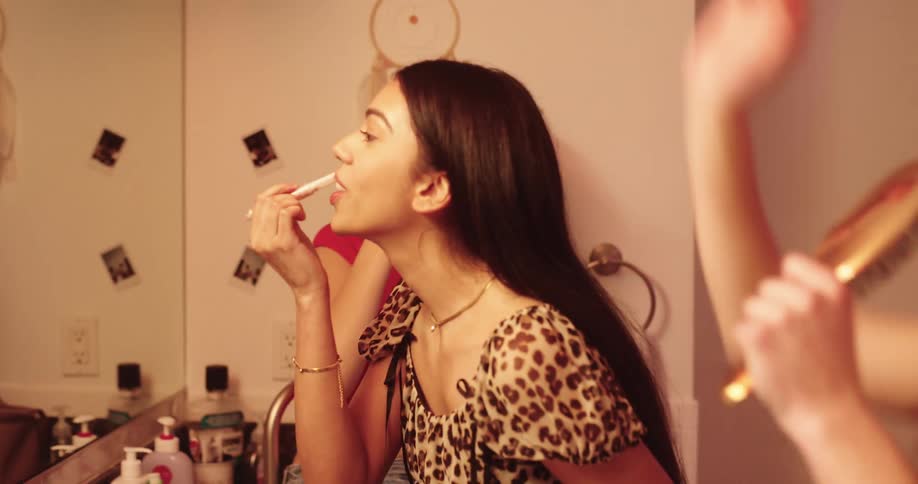 Teenage girls having fun dancing while putting on makeup in the bathroom at home