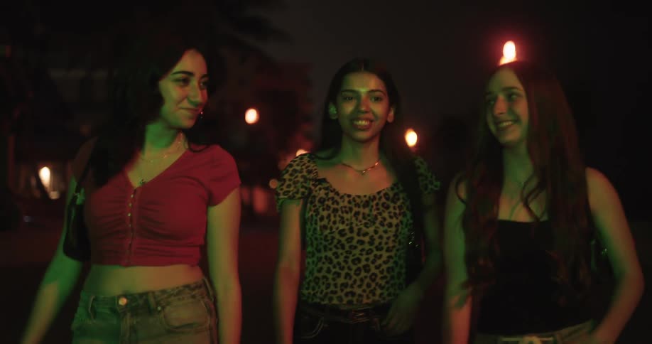 Three happy women walking outdoors at night