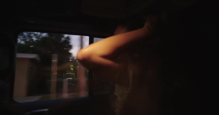 Woman sitting in the back seat of a car having fun dancing