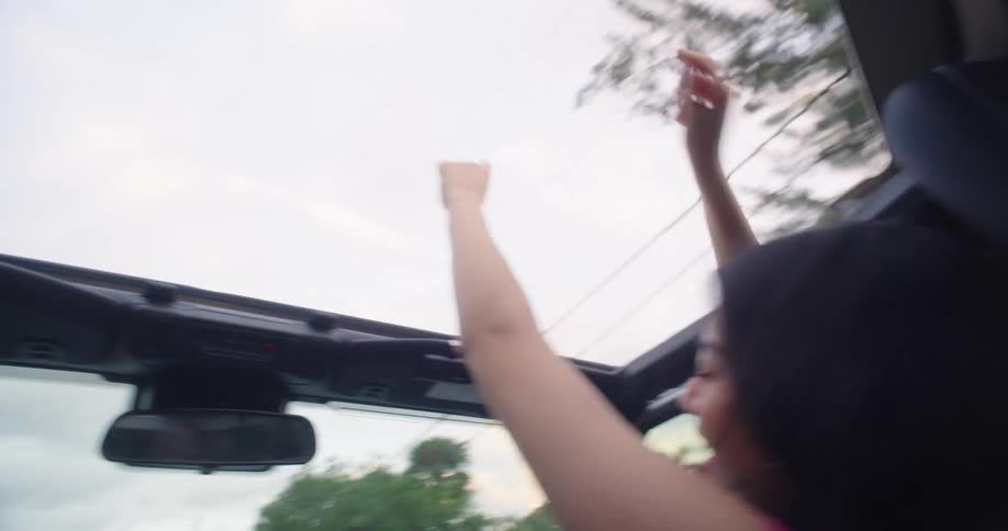 Woman sitting in the front seat of a car cheering happily