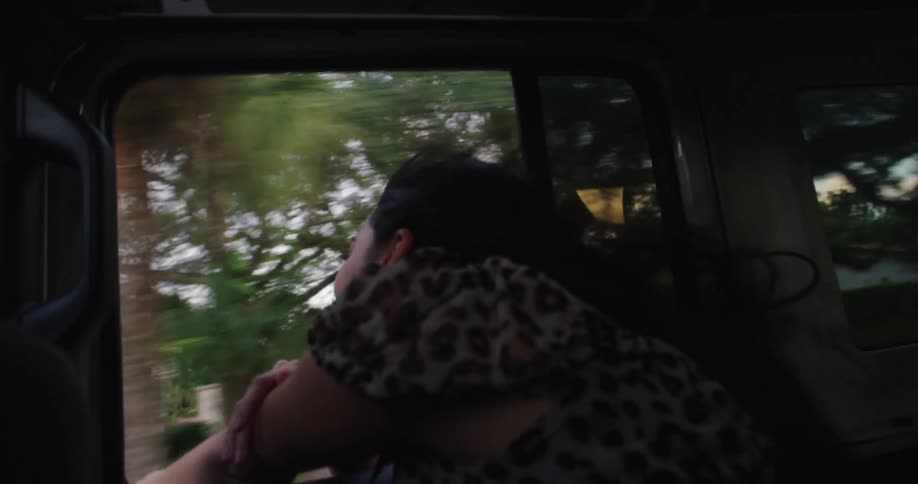 A girl is laughing near the open window in a car her hair flowing in the wind having fun and enjoying the moment
