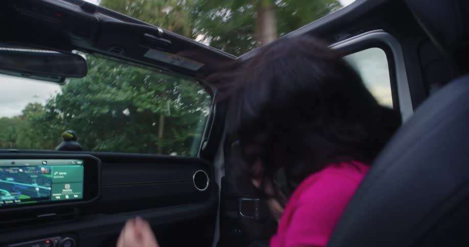 Woman in the front seat of a car dancing and singing happily