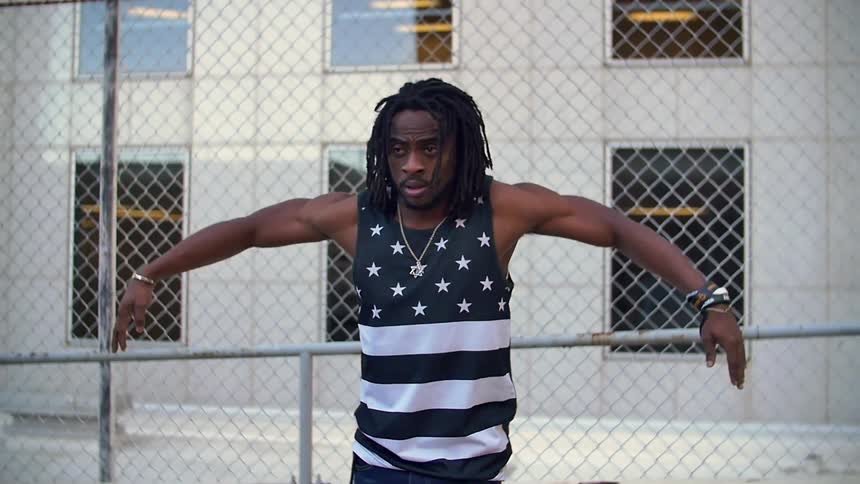 A man is dancing near a fence by a building