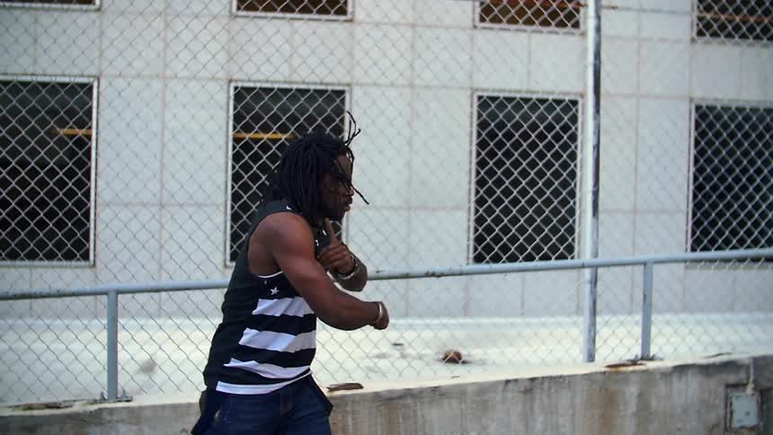Man dancing outside in front of fence