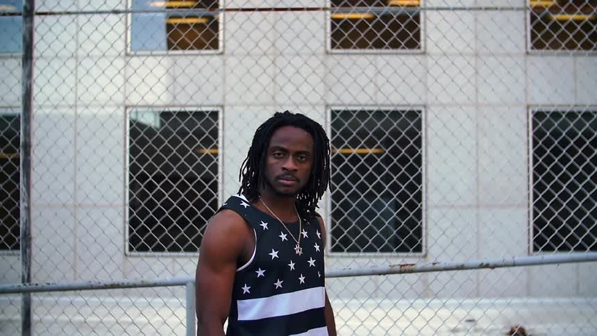 A man stands in front of a chain link fence