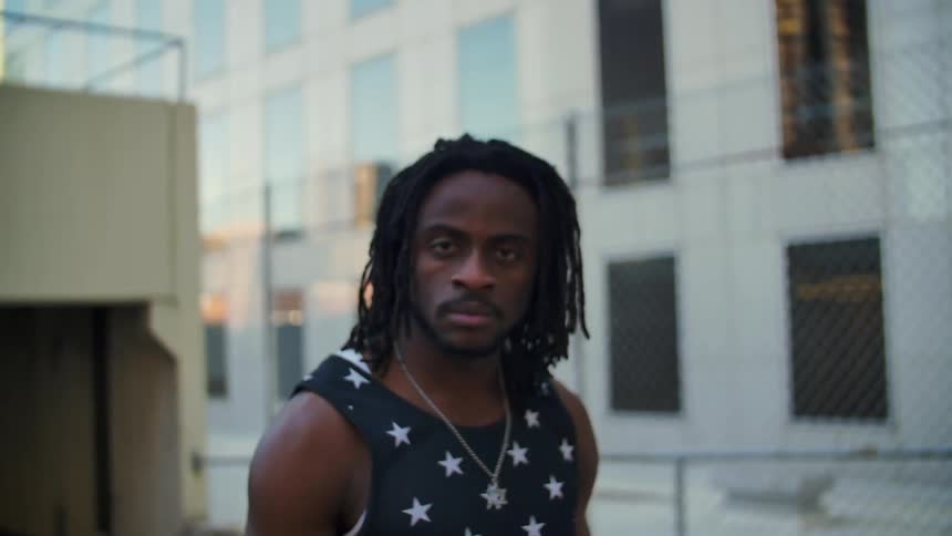 Man wearing a patriotic tank top  looking into a camera as it's zooming in