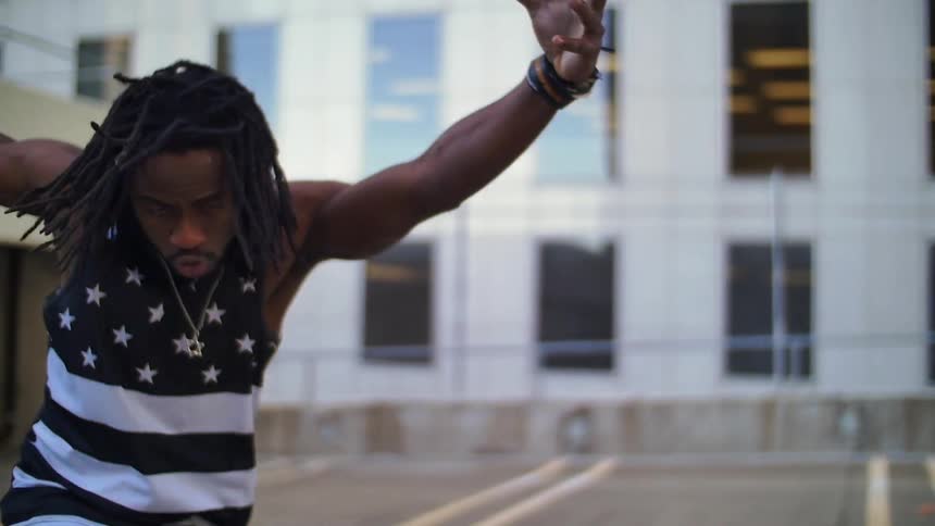 A man wearing a tank top dances in a parking lot