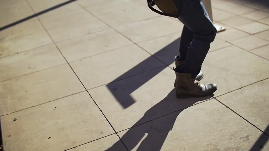 A person dancing wearing boots on a sidewalk or secluded area