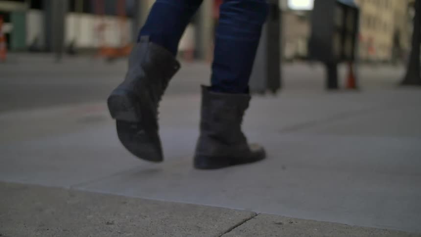 View of a person's feet walking down the street downtown
