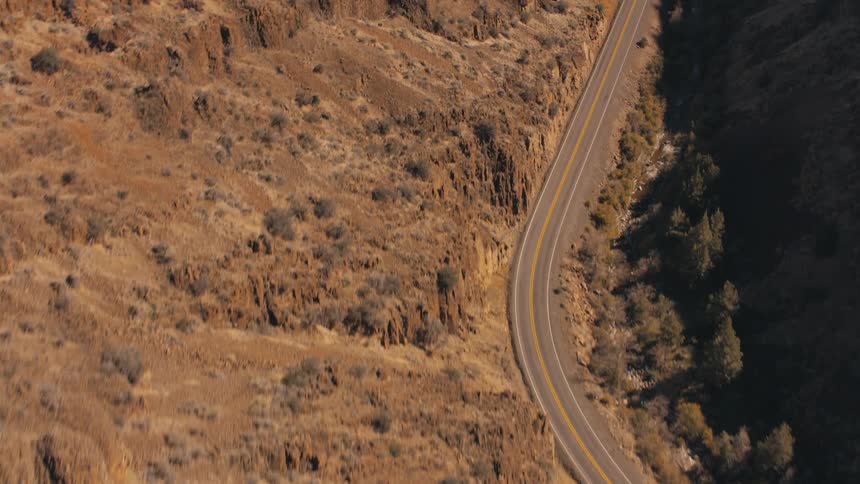 Aerial view of a winding asphalt road amidst mountains