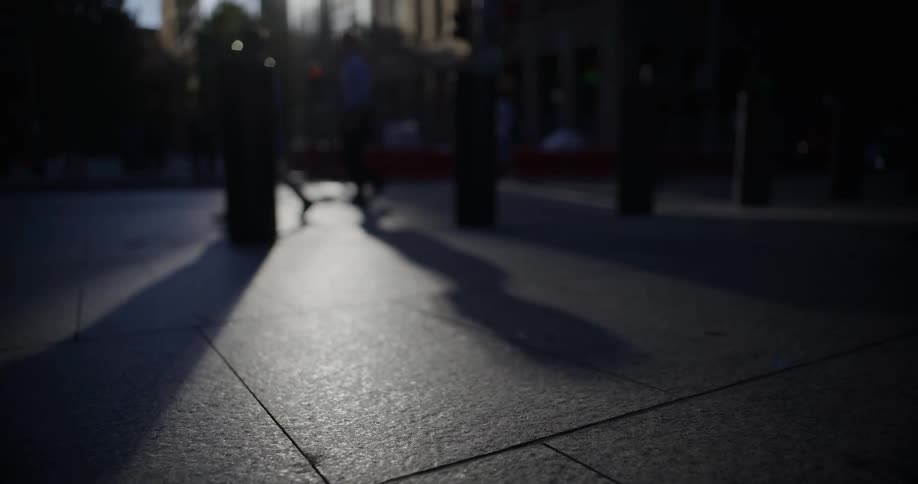 The shadows of several people walking across a paved surface