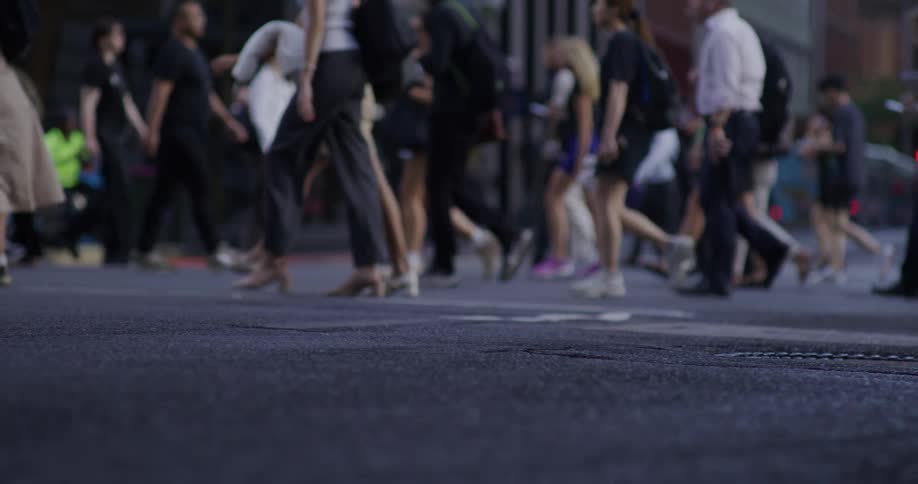 A busy urban street scene with numerous people walking in various directions