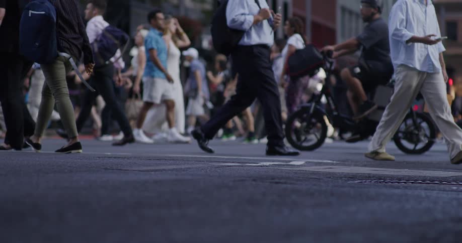 A busy urban street scene with numerous people walking in various directions