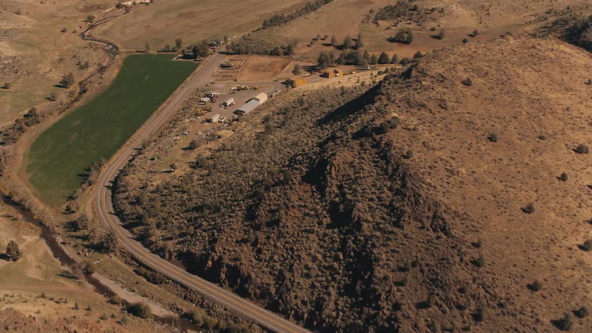 Aerial view of a long highway that passes through a natural area with sparse vegetation