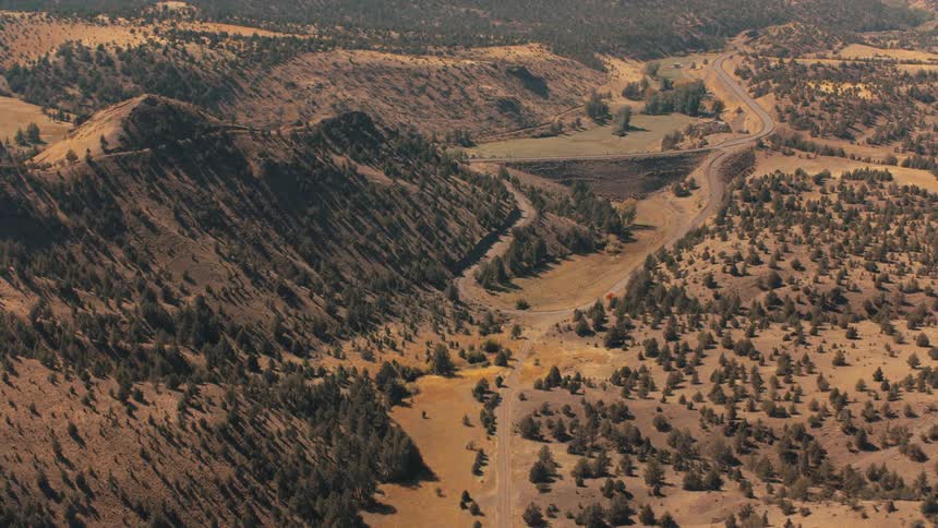 Aerial view of a winding road passing through a valley and mountain range