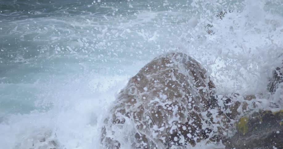 Waves crash against the rocks on a sunny day