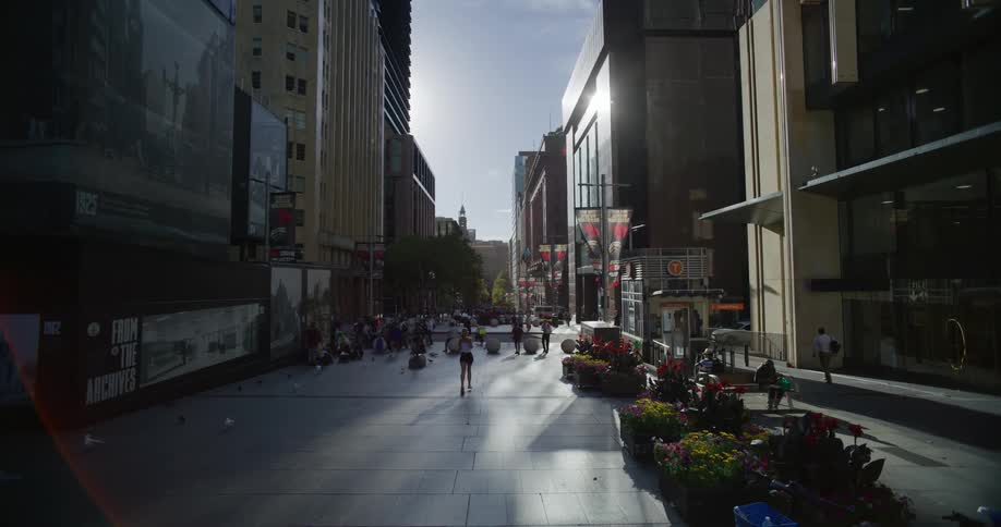 A woman runs down a city street lined with buildings and people