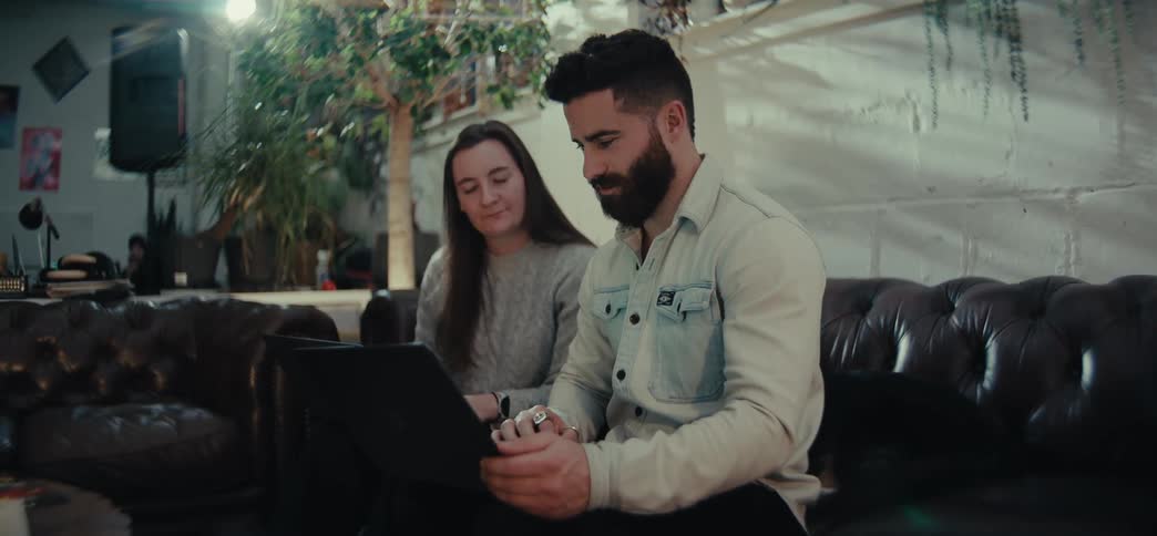 Woman and a man sitting in an armchair in front of a laptop