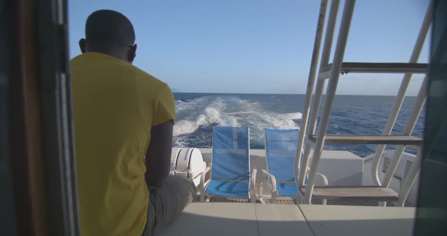A man is sitting on a moving boat on a sunny day