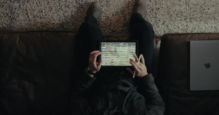 An adult is sitting indoors and scrolling on an electronic tablet