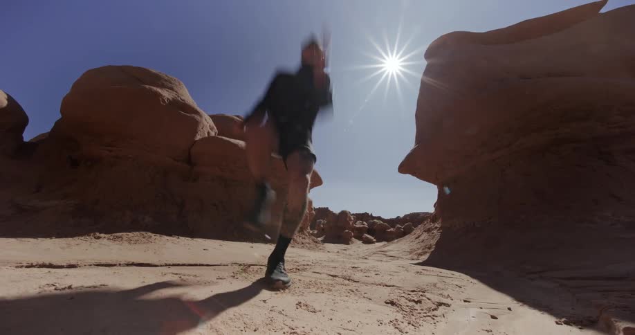 Man running at high speed in a desert area with rocks around