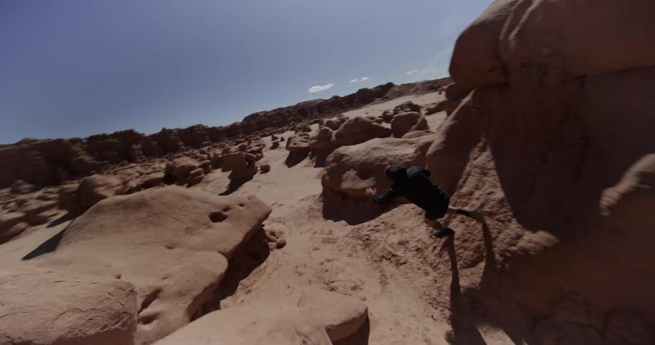 Person jumping and running between desert rocks