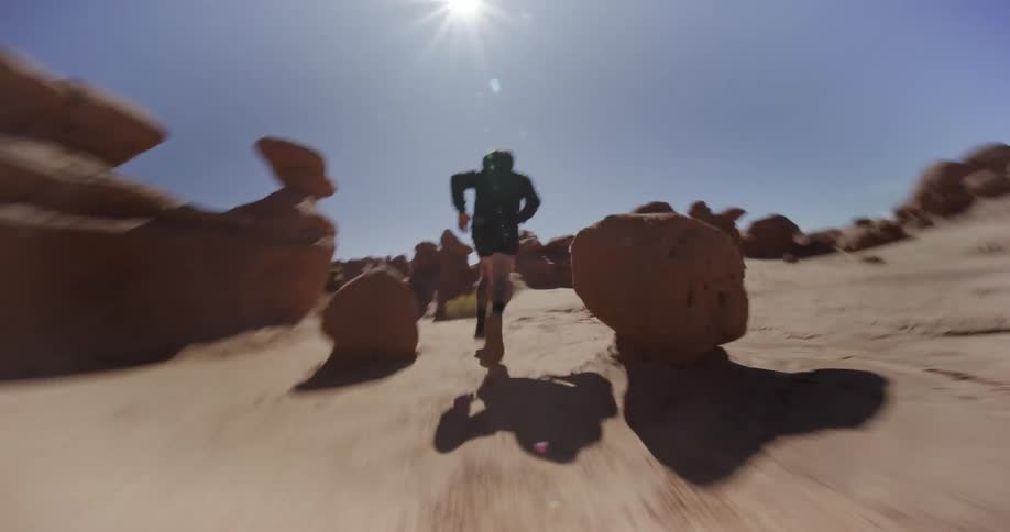 Man running in a desert landscape with rock formations during daytime
