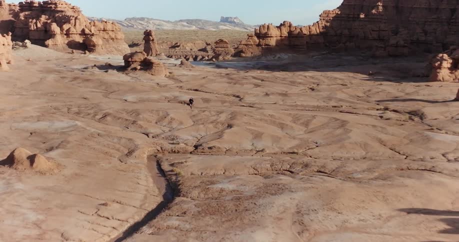 An adult is running in a desert valley on a mostly sunny day