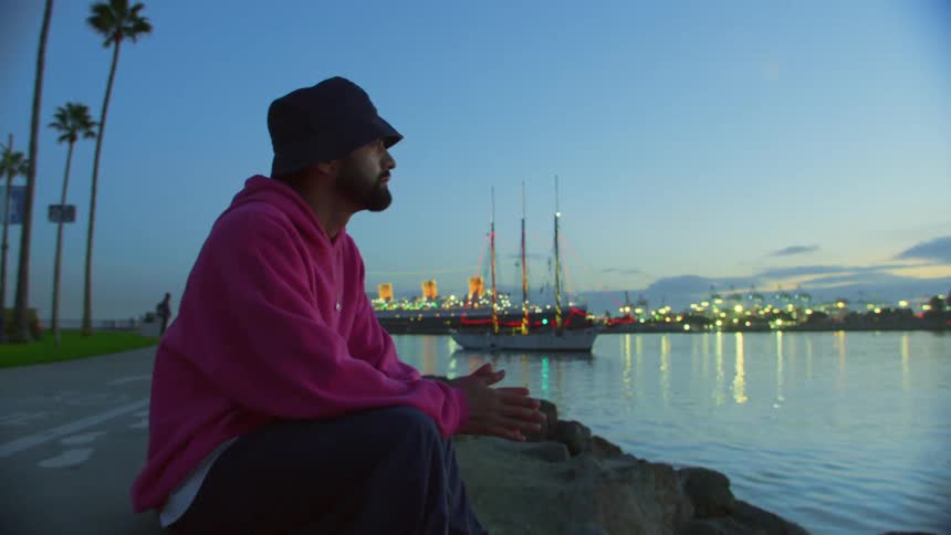 A man is looking out over the coast at sunset