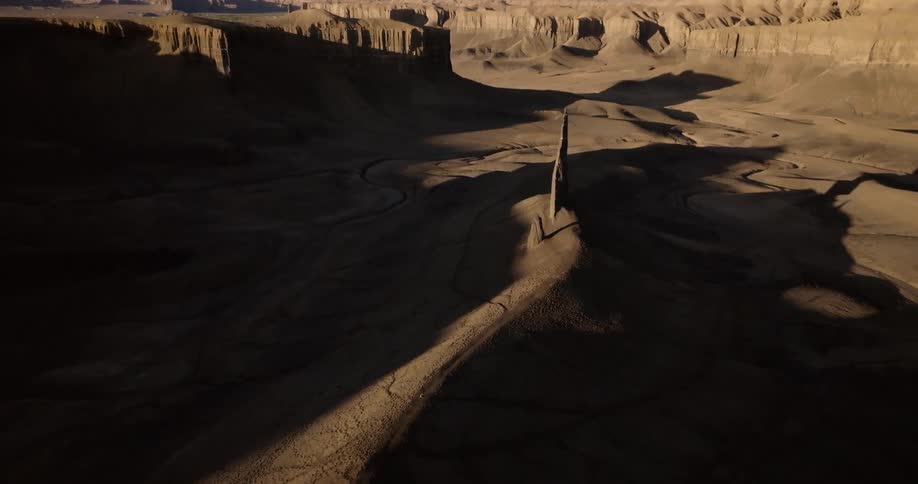Aerial shot of a desert region with rock formations and cliffs and a person running