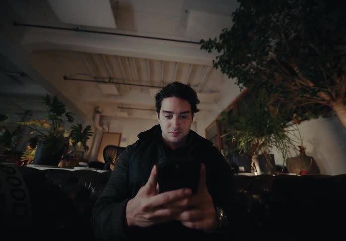 A man is using his phone on the couch