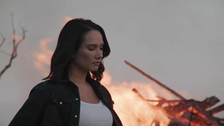 Woman outdoors with a high fire in the background