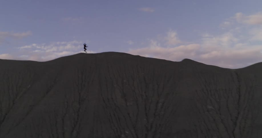 Silhouette of a person running down a mountain cliff
