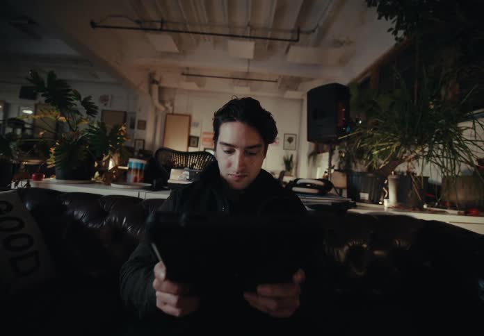 Man sitting in an armchair and starting to use a tablet