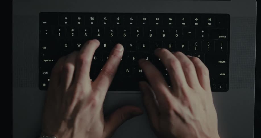 Overhead view of hands typing on a laptop keyboard