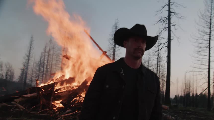 A footage of a man walking away from a burning fire