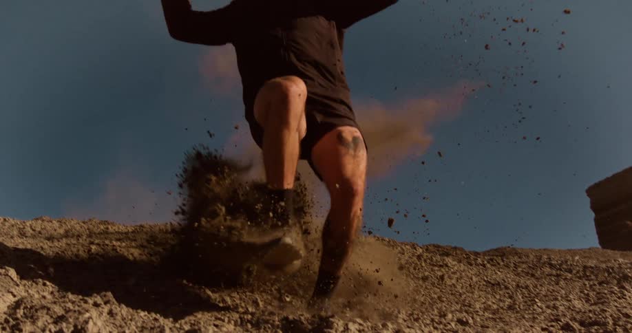 Man in jacket and sunglasses running down a ravine