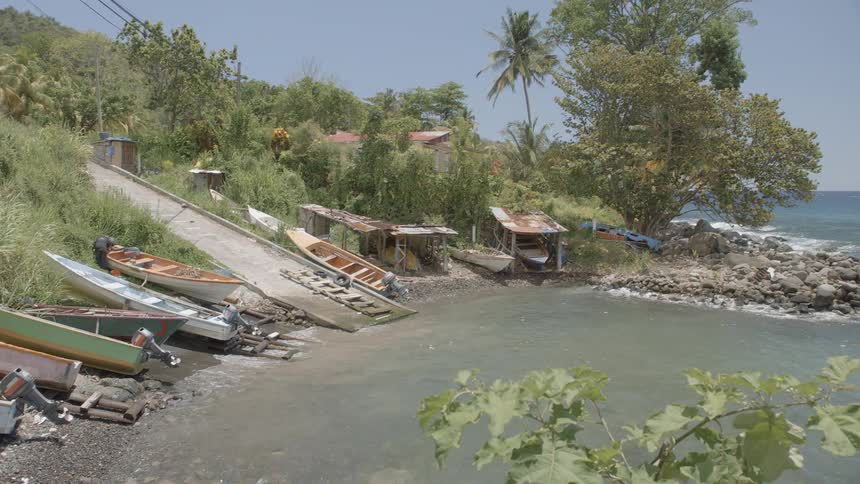 A row of small boats are on the shore near the rocks