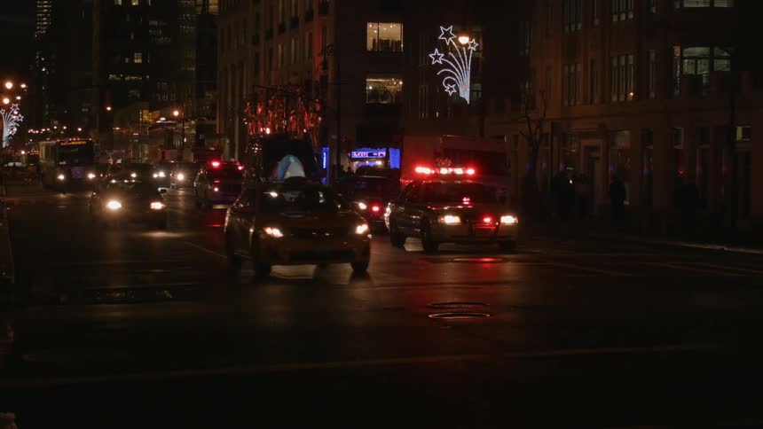 A large city at night filled with cops and flashing lights as other cars pass by them
