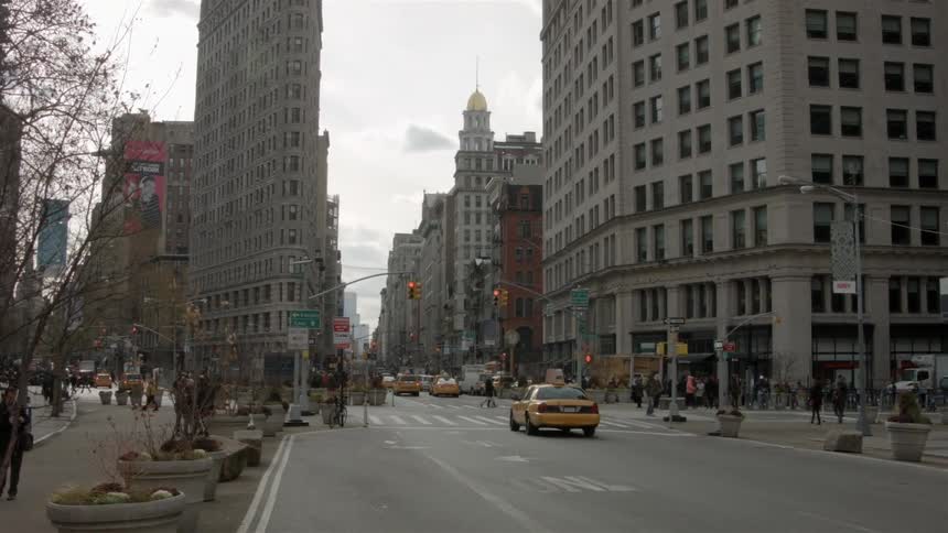 A cab stopped at a red light as people cross the street in this city