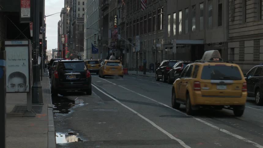 Taxi cabs driving down a street in the middle of a city