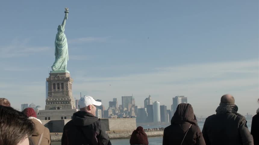 A group of tourists pass the statue of liberty