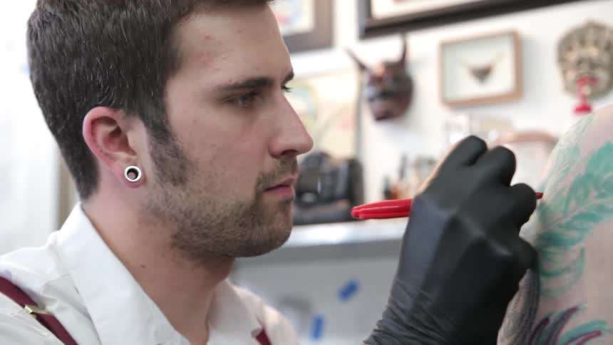 Man working on a tattoo on a person's shoulder