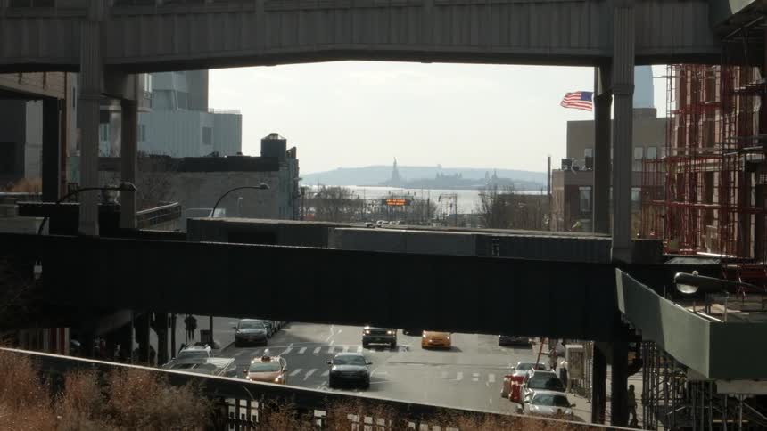 Cars driving in a city that has a large bridge way above