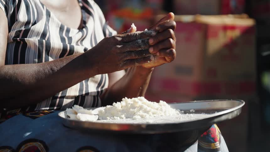 Pair of womans hands kneading flour on top of a metal container